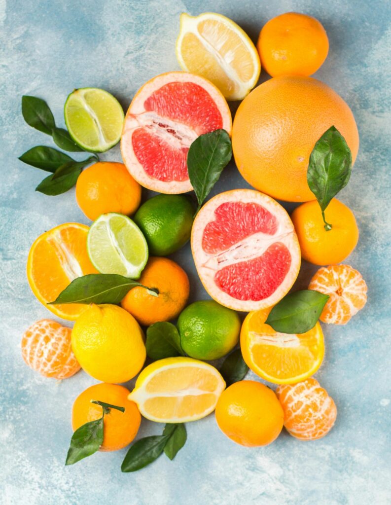 Colorful assortment of fresh citrus fruits including grapefruits and lemons on a vibrant blue background.