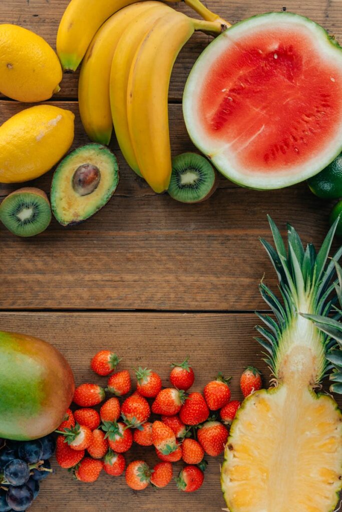 Colorful assortment of fresh fruits in a flatlay on wooden surface, perfect for healthy lifestyle themes.